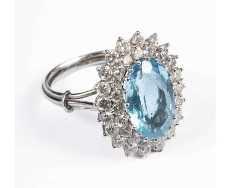 A blue topaz and diamond cluster ring, the oval topaz approximately 15mm x 9.9mm x 6mm, within a double border of round brill