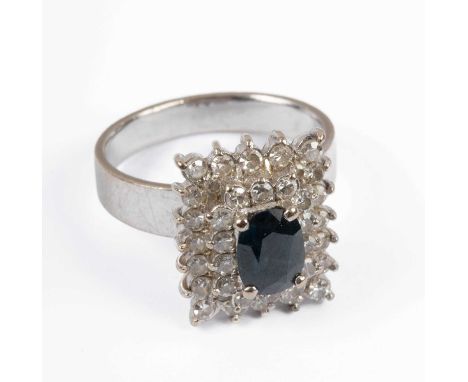An 18k white gold, sapphire and diamond rectangular cluster ring, the central oval cut sapphire within a stepped border of ro