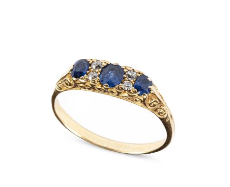 An Edwardian sapphire and diamond dress ring, set with three graduated oval cut sapphires and four old cut diamonds, in scrol