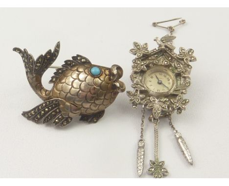 Amusing marcasite brooch watch modelled as a cuckoo clock and another, in silver, as a fish. (2).