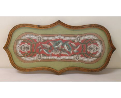 Victorian tapestry and beadwork table stand of lobed oval form, the floral panel in glazed walnut frame on four circular feet