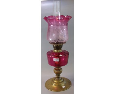 Early 20th Century double oil burner lamp, having frosted cranberry glass shade, above a cranberry glass reservoir on a brass