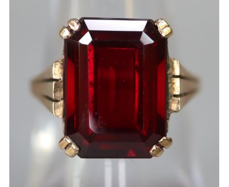 9ct gold dress ring set with a step cut red stone. Ring size M & 1/2. Approx weight 4.7 grams. (B.P. 21% + VAT) Condition is 