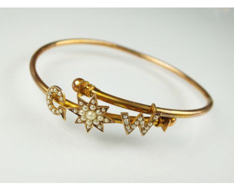 An early 20th century seed pearl bangle, the crossover torque set with split seed pearl 'G' and 'W' flanking seed pearl set s