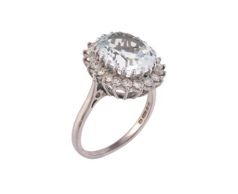 A 1970s aquamarine and diamond cluster ring, the oval cut aquamarine within a surround of brilliant cut diamonds, approximate