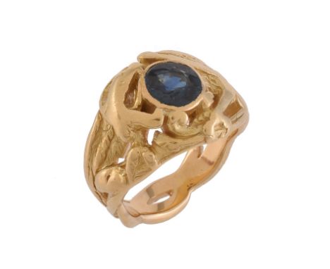 An Art Nouveau sapphire chimera ring, circa 1900, the ring carved as a chimera grasping a circular cut sapphire in its open j
