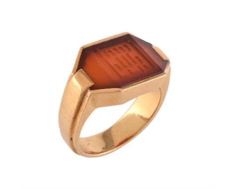 A French Art Deco cornelian dress ring, circa 1920, the polished facetted panel engraved with a geometric symbol, to a steppe