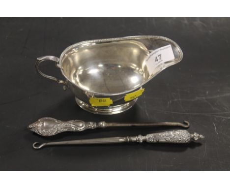 A HALLMARKED SILVER SAUCE BOAT, TOGETHER WITH TWO SILVER HANDLED BUTTON HOOKS