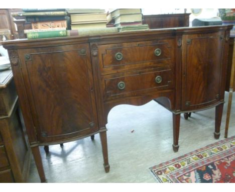 An early 20thC mahogany sideboard, having a low upstand, over two central drawers, flanked by a pair of bow front cupboards, 