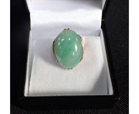 A JADEITE COCKTAIL RING in 9ct gold, set with a jadeite jade cabochon, stepped shoulders, no assay marks, UK size H1/2 / EU s