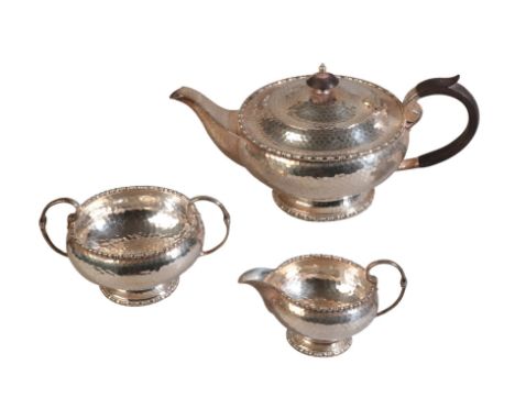 AN EARLY 20th CENTURY SILVER PLATED THREE PIECE TEA SERVICE by Walker and Hall, with planished bodies, comprising teapot, mil