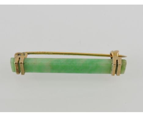 A Chinese jade bar brooch in a yellow metal mount.