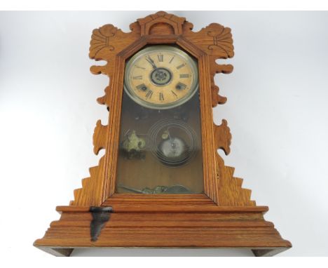An early 20th century Ansonia mantel alarm clock, the oak case with a glazed panel door with canted corners, on a moulded bas