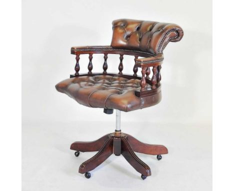 A modern brown leather revolving desk chair, with a button back