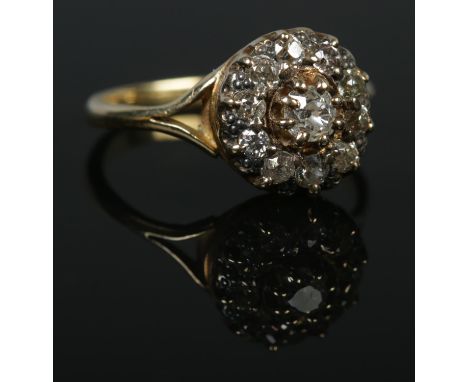 An 18ct gold and diamond cluster ring. Centre stone approximately 0.2ct. Size S. 4.87g.  Would benefit from a clean.