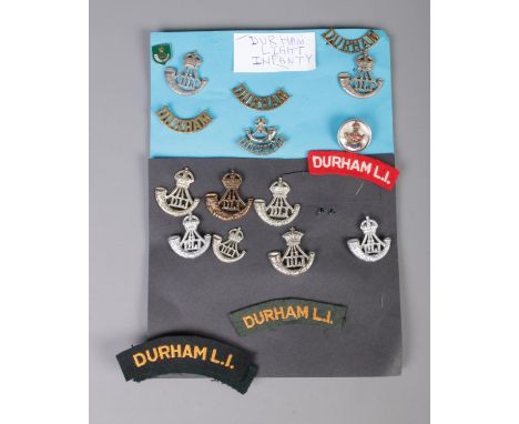 A collection of Durham Light Infantry cap badges and patches including silver and mother of pearl example.  