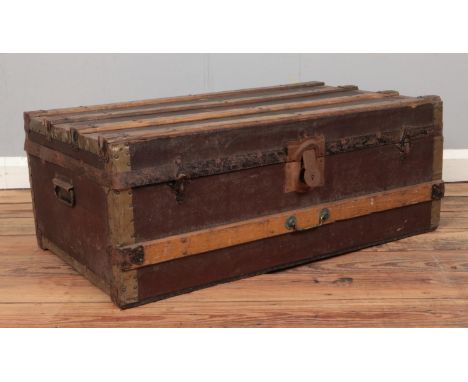 A wooden bound hinged top trunk, with tin base. Height: 32cm Depth: 47cm Width: 83cm.  