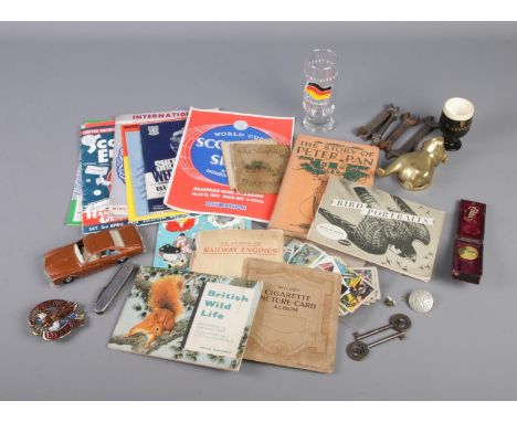 A box of collectables including brass bull door knocker, cigarette cards, football programmes, etc.  