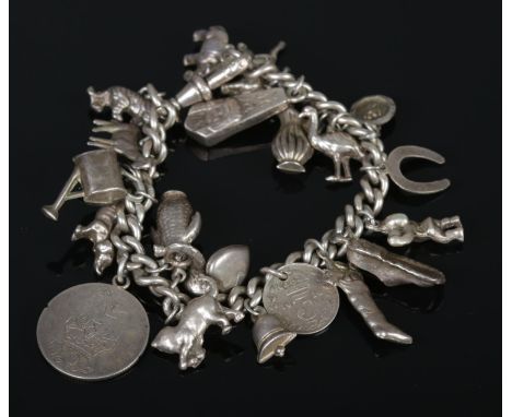 An old curb silver charm bracelet, containing several dog charms, 1918 three pence piece, watering can, bugle etc. Total weig