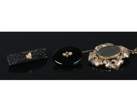 Three Victorian mourning brooches, including large scrolled yellow metal with safety chain and chequered bar examples.  Repai
