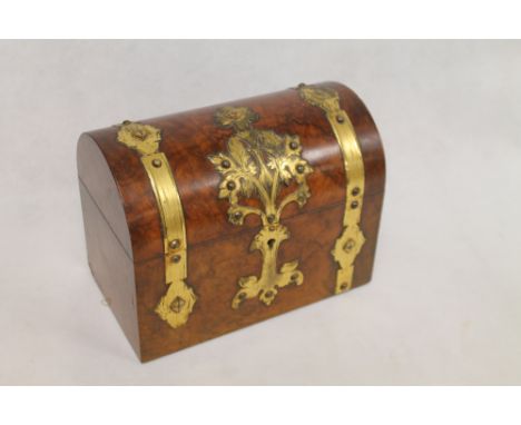Victorian burr walnut tea caddy of domed rectangular form with Gothic style brass banding and foliate mounts, the interior wi