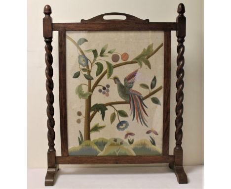 Crewel work tapestry firescreen in oak frame with barley twist columns, decorated with a bird in a flowering tree, 79cm high.