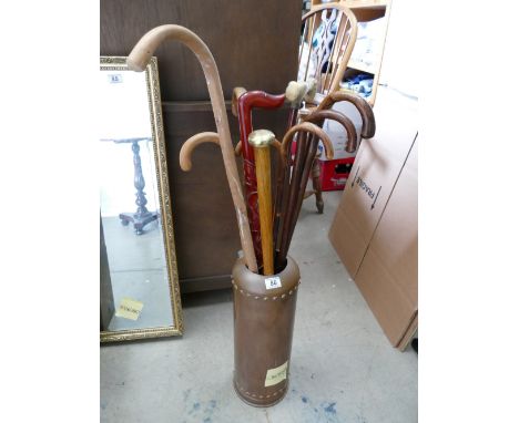 Collection of vintage wooden walking sticks in a brass stand made from a canister of type 