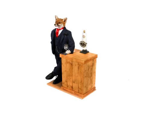 An anthropomorphic taxidermy red fox, Vulpas Vulpas. Modelled leaning against a bar, dressed in a navy blue suit with a red t