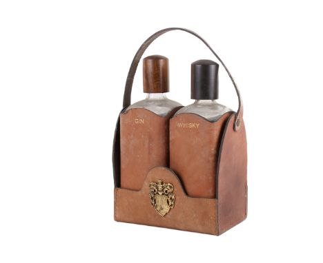 A leather tantalus and two decanters. The stitched leather tantalus with brass coat of arms to the front, the two leather cas