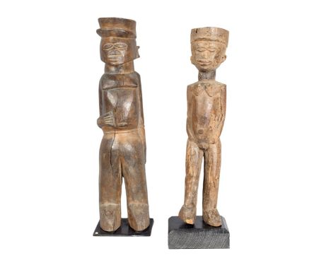 A Lobi standing figure, Burkina Faso, wearing a peaked cap, with his right hand on his abdomen, with waist band and bangle, s