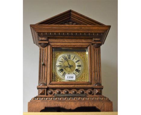 A late 19th century oak architectural mantel clock, twin winding holes, Roman numerals, silvered chapter ring, presentation p