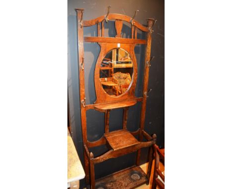 An oak hallstand circa 1940's, with mirrored panel to centre, above stick stand recess and hat and coat hooks, 199cm high x 7