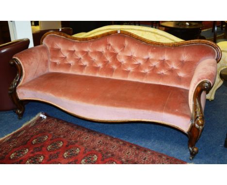 A Victorian mahogany scroll back settee, upholstered in pink button back velour, raised on carved scroll supports, 90cm high 