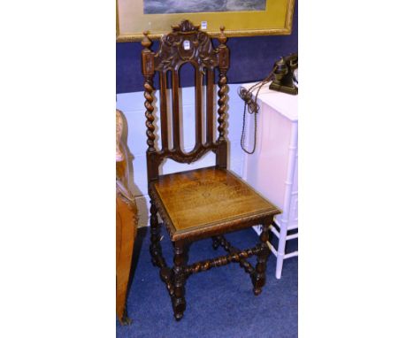 A Victorian style carved oak hall chair, the carved top rail flanked with turned finial above rails and barley twist columns,