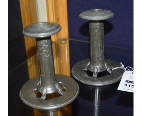 A pair of Liberty style pewter candlesticks by Tudric, with detachable sconces, tapering stem and ending in pierced stylized 