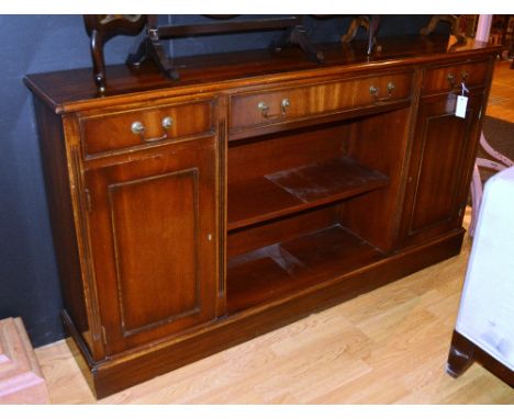 A reproduction open bookcase, with central drawer flanked by smaller drawer, above open shelf flanked by panelled cupboard do