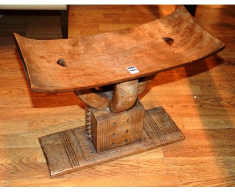 An African stool, with sleigh style top, raised on ornate supports and plinth base, 34cm high x 51cm wide x 23cm deep