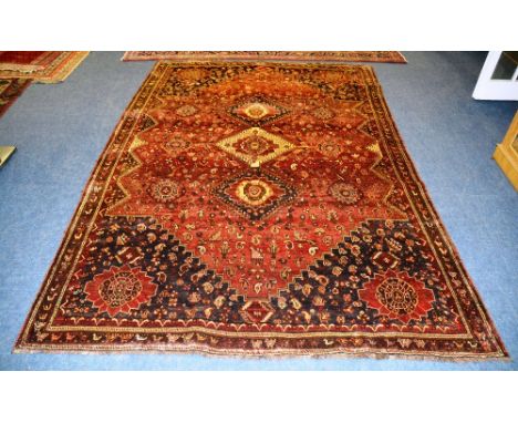 A Shiraz carpet, with triple diamond inset with rosette over red ground with botas, rosettes, birds and matching spandrels, w