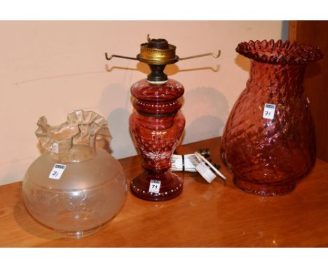 A cranberry glass oil lamp, decorated with white painted floral panels, with etched clear glass shade, converted, 54cm high, 