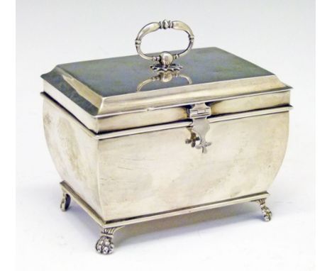 George V silver rectangular tea caddy of sarcophagus form, the hinged cover with oval loop handle, standing on four paw feet,