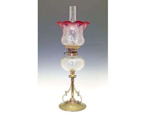 Late 19th/early 20th Century oil lamp having a cut glass reservoir and standing on a brass triple scroll base with a circular