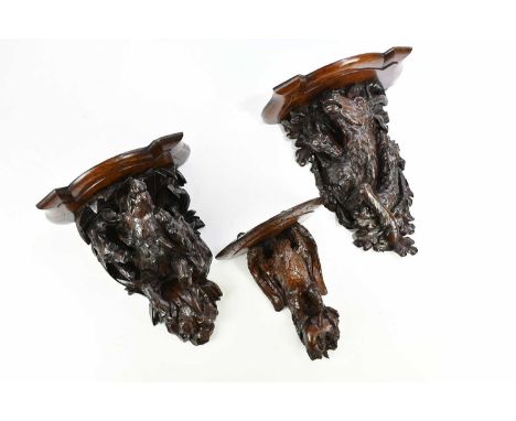 Three Black Forest carved oak wall brackets, including an example modelled as a hunting scene depicting dogs attacking a stag