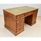 A reproduction burr walnut kneehole desk, with tooled green leather inset top above an arrangement