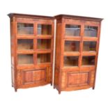 A pair of modern walnut effect display cabinets with moulded cornices above six glazed doors and a