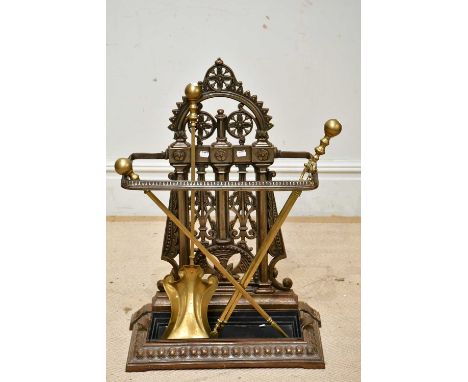 A reproduction cast iron stick stand with pierced arched back, height 79cm, and a set of three 19th century brass fire irons 