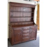 A reproduction oak dresser with boarded plate rack back above seven spice drawers, the base