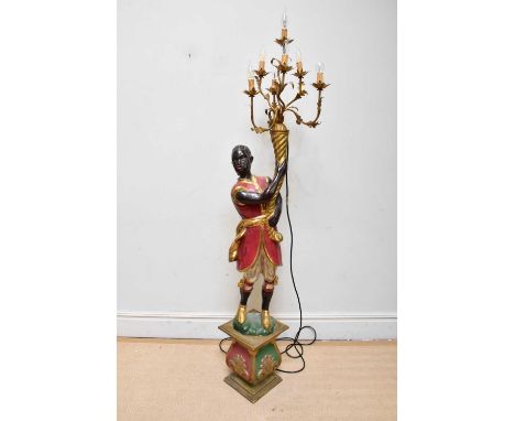 A modern painted and gilt wood blackamoor floor standing lamp, the figure holding a gilt metal seven branch light, on a shape
