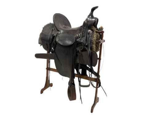 19th/ early 20th century Western leather stock saddle with tooled decoration, wooden stirrups, eight plated conchos with tie 