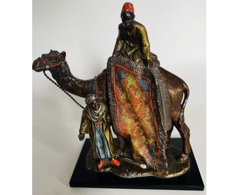 An Austrian cold painted spelter table lighter in the style of Bergman, cast as two carpet sellers and a camel on a rectangul