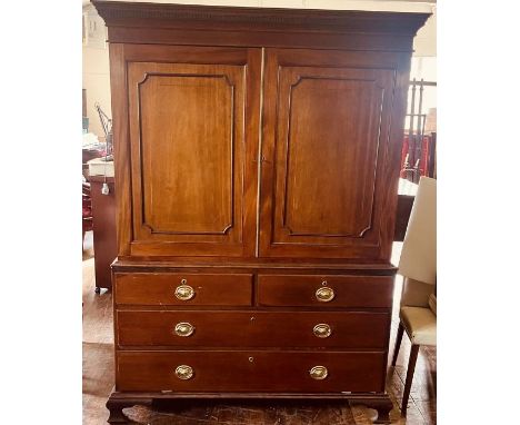 A George IV mahogany linen press, circa 1820, moulded on a dental cornice, above twin moulded and satinwood strung panel door